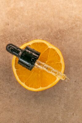 Hücrelerin Koruyucu Kalkanı: E Vitamini Hakkında Kapsamlı Bilgiler Top view of a fresh orange slice with a dropper, showcasing a close-up of vibrant citrus and liquid texture.