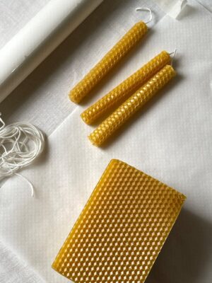 Flat lay of handmade beeswax candles with crafting materials, highlighting natural textures.