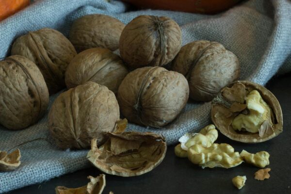 A collection of whole and cracked walnuts on a rustic textile surface, offering a natural vibe.