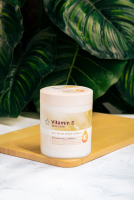 Hücrelerin Koruyucu Kalkanı: E Vitamini Hakkında Kapsamlı Bilgiler Vitamin E skincare cream on wooden board, lush plant background.
