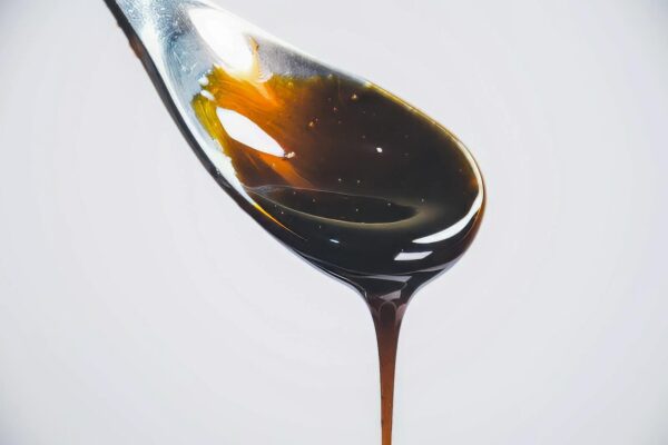 Artistic close-up of honey dripping from spoon against bright background, highlighting texture.