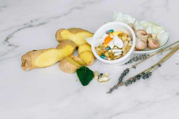 A flat lay featuring ginger, garlic, and various herbal supplements on a marble surface.