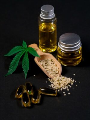 A set of CBD products including oil, capsules, hemp seeds, and a cannabis leaf, presented on a dark backdrop.