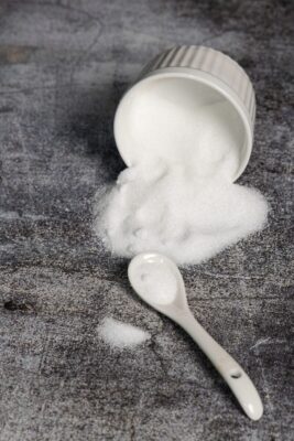 a scoop of sugar sitting on top of a table next to a spoon