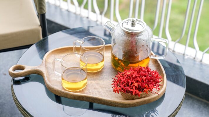 Glass teapot with tea and cups on a wooden tray