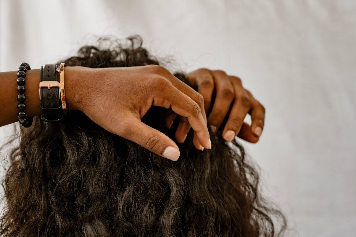 Detailed image of hands styling curly hair, showcasing accessories and a natural hairstyle.