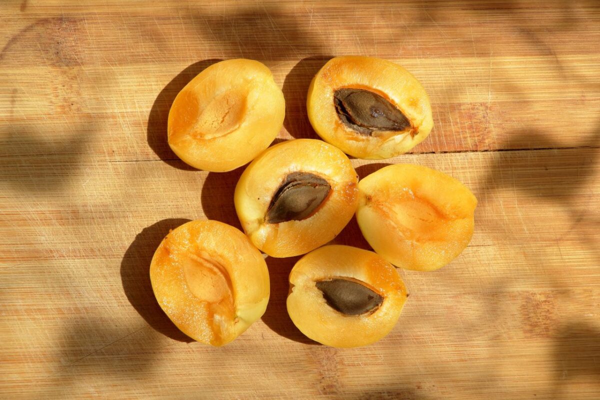 Fresh halved apricots with seeds on a wooden board, perfect for healthy recipes.