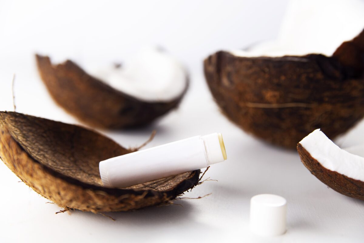 Close-up of a natural lip balm amidst coconut shells, showcasing organic skincare products.