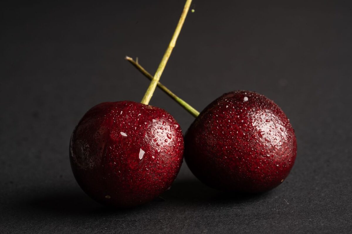 Vibrant close-up of fresh cherries with water droplets on a dark backdrop, highlighting texture.